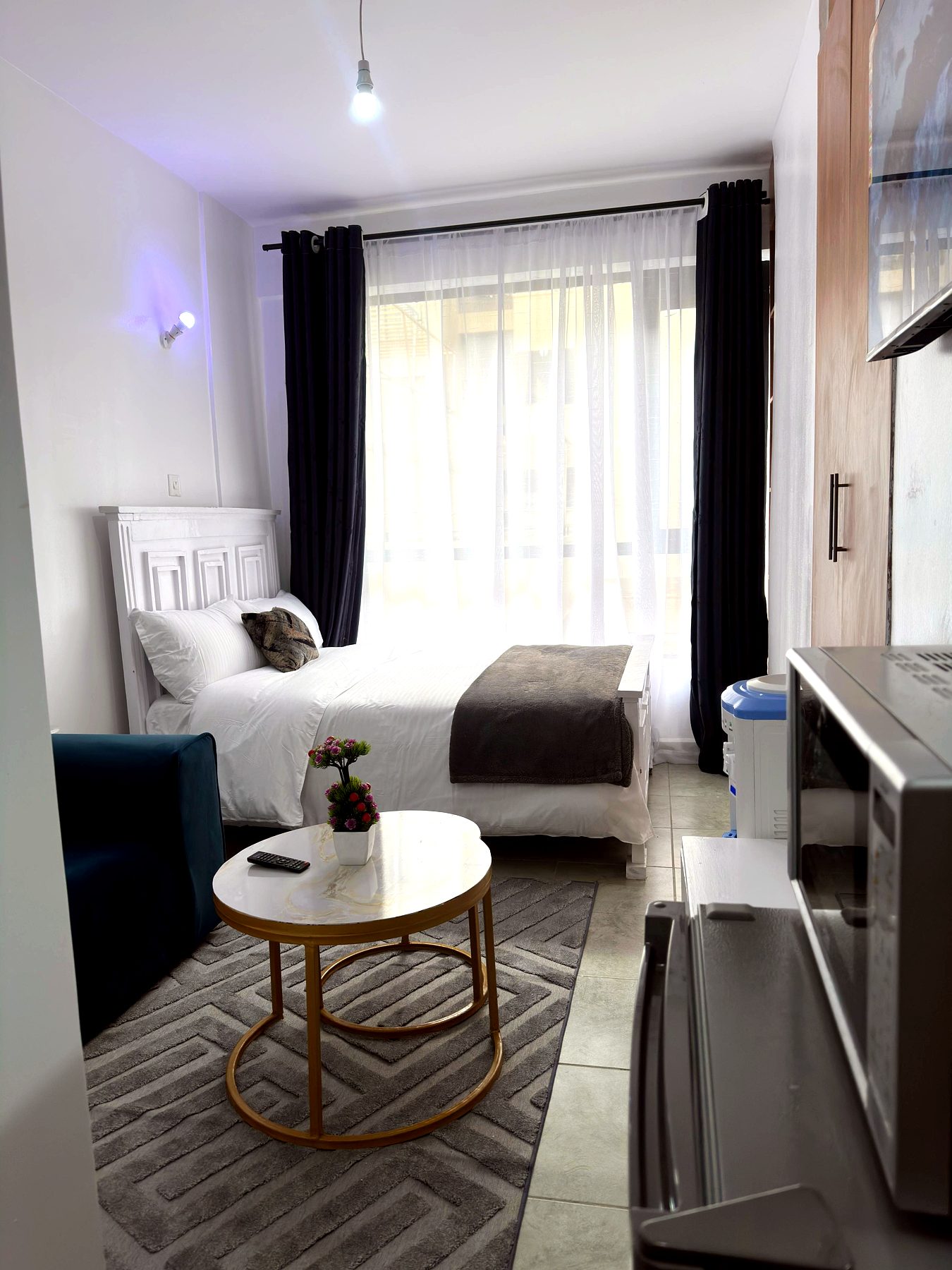Studio bedroom with white bed, coffee table and city view