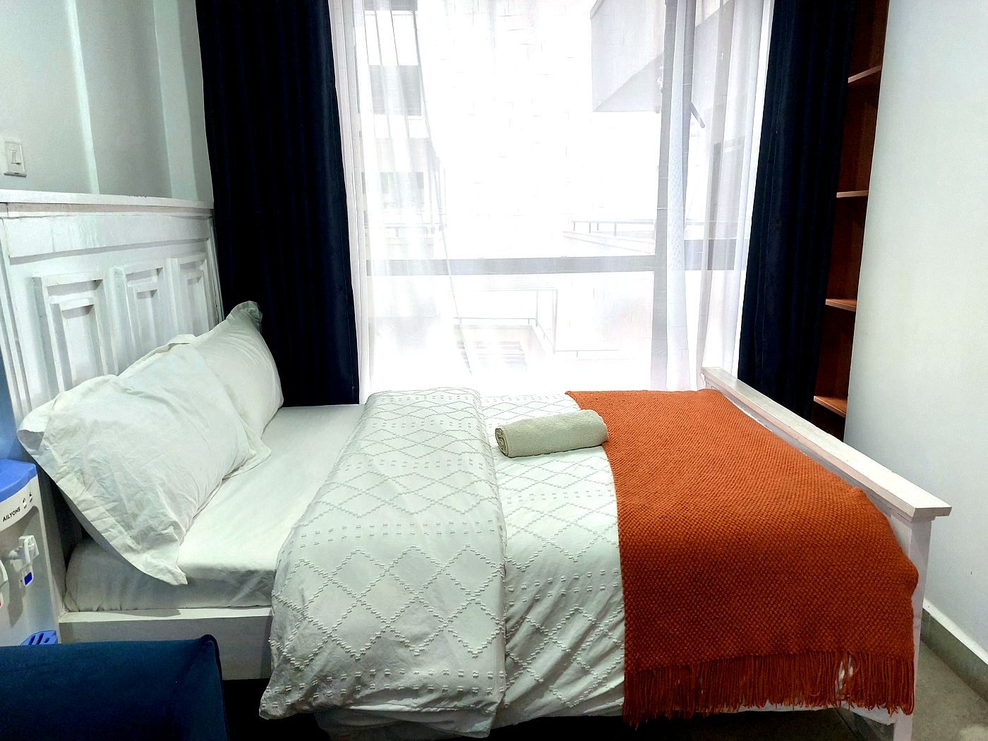 Studio bed with orange throw blanket and city view window